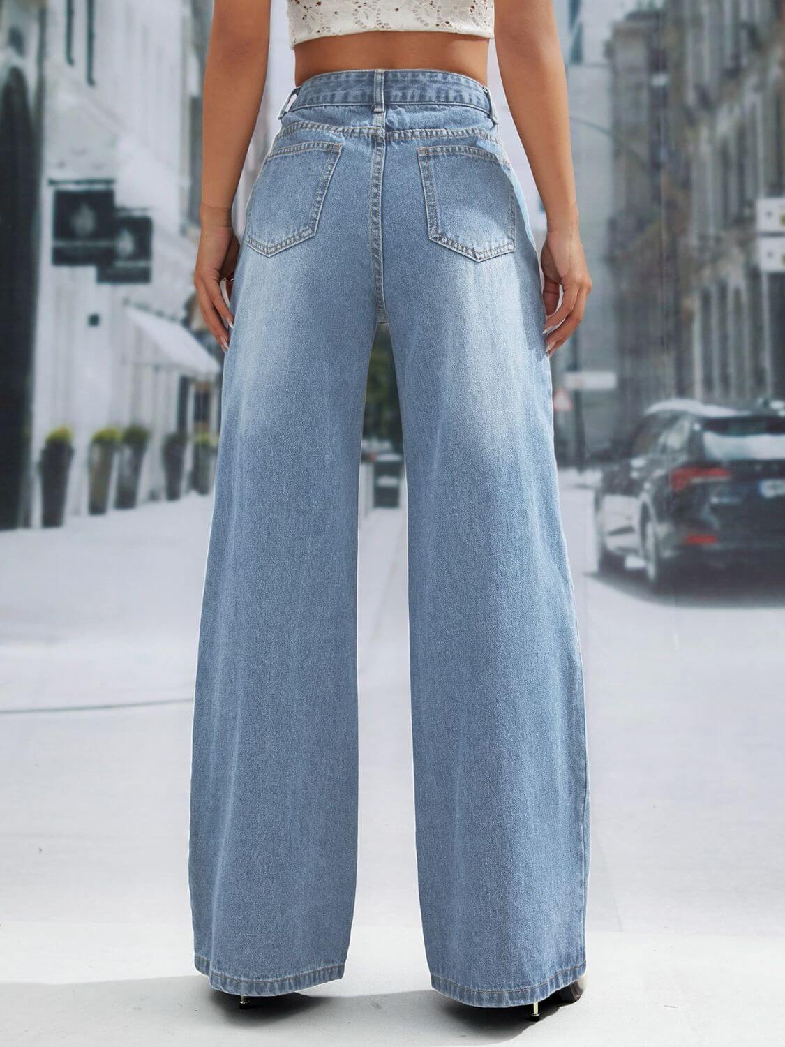 Woman wearing wide leg jeans with pockets, buttoned and slightly stretchy, standing on a city sidewalk, showcasing back view of jeans.