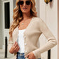 Woman wearing Bella Road Button Up Long Sleeve Cardigan, beige color, with white top and jeans, accessorized with sunglasses and necklace, stylish street attire