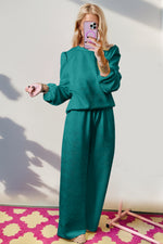 Stylish woman in teal Double Take Texture long sleeve top and wide leg pants set, showcasing quirky and playful fashion.