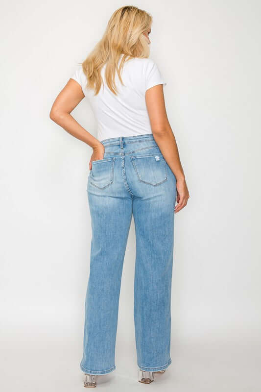 Woman showcasing distressed high rise straight jeans from the back, paired with a simple white t-shirt.