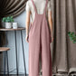 Woman wearing ribbed front pocket sleeveless jumpsuit in pink, viewed from the back, standing in a stylish, modern room with chic decor.