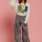 Model wearing LOVE graphic sweatshirt and floral pants against a pink background, showcasing casual and stylish vibes.