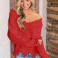 Woman wearing Bella Road frayed hem dropped shoulder sweater in red, cozy and stylish look