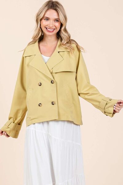 Stylish woman in a double-breasted long sleeve trench coat jacket, smiling and showcasing a chic, layered look.