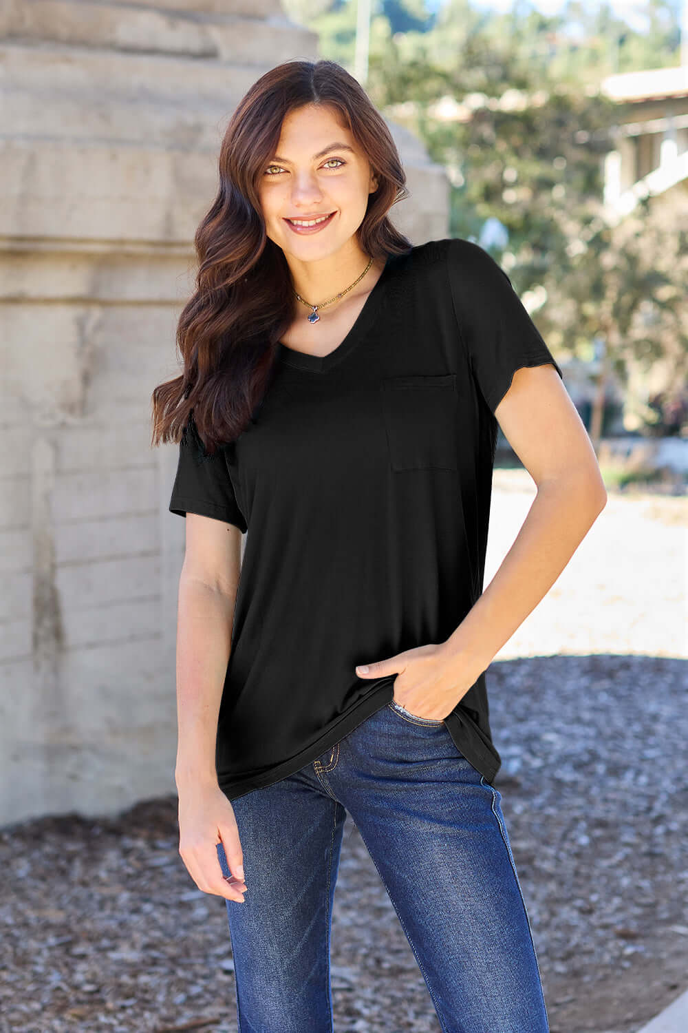 Woman wearing Basic Bae Bamboo V-Neck Short Sleeve T-Shirt in black, styled with blue jeans, standing outdoors.