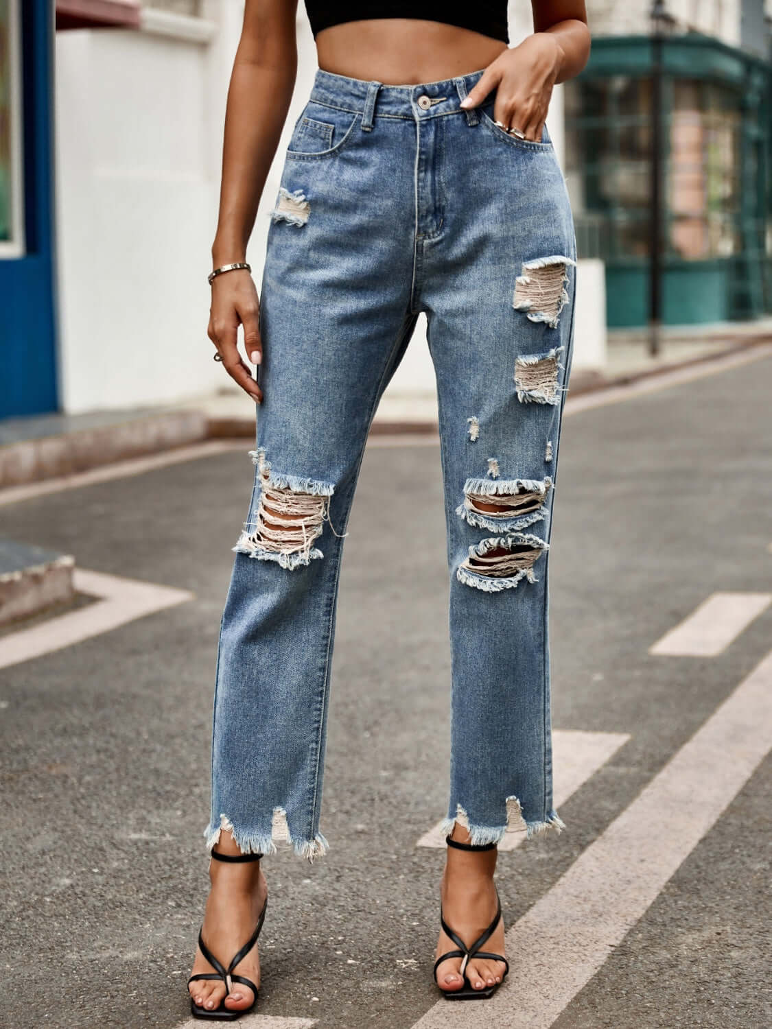 Woman wearing Bella Road Distressed Raw Hem Jeans with Pockets, showcasing the slightly stretchy, pocketed, and ripped design in a street setting.