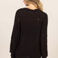 Woman wearing a black HYFVE distressed long sleeve knit top with a relaxed fit and drop shoulders, showcasing a chic and comfy style.