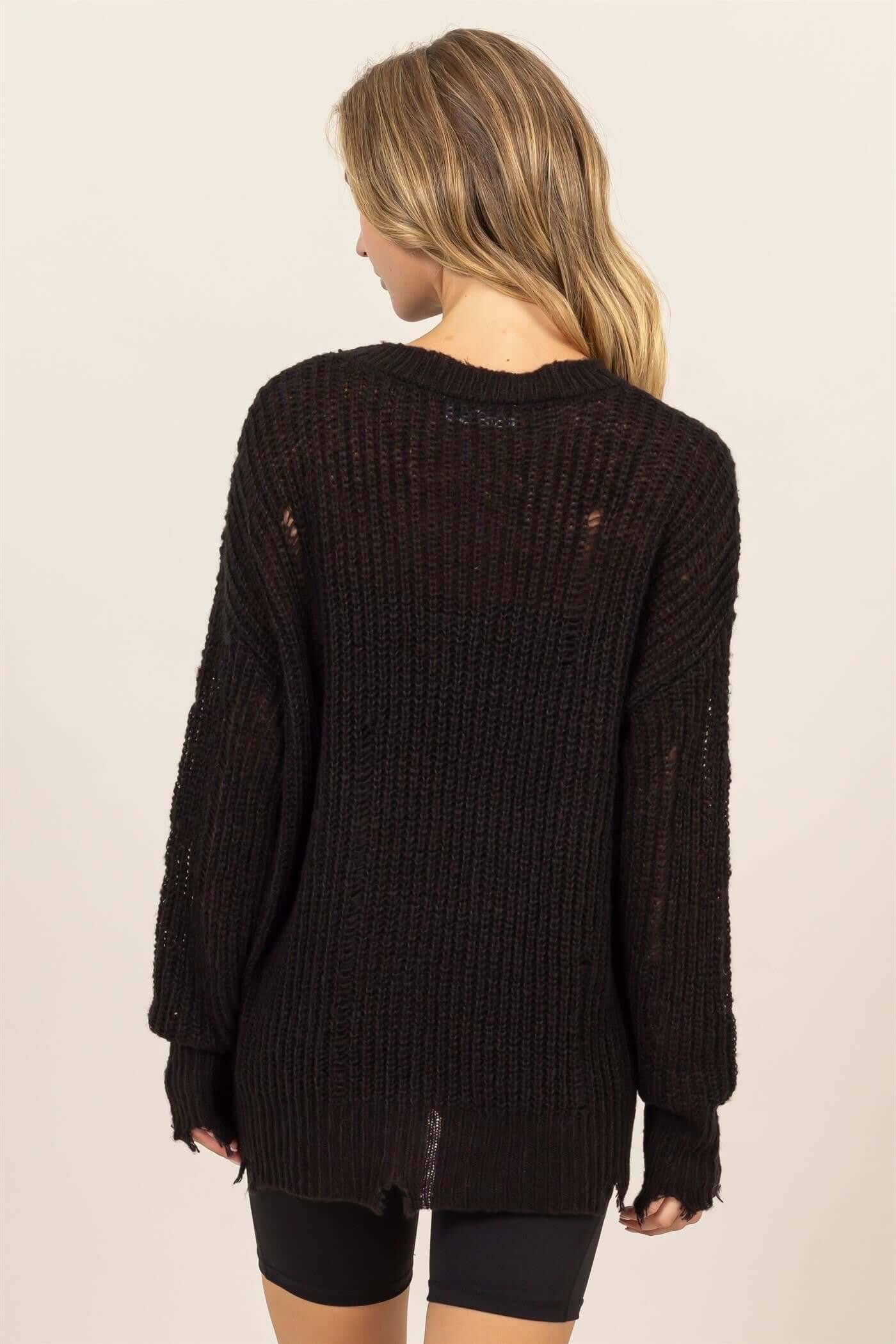 Woman wearing a black HYFVE distressed long sleeve knit top with a relaxed fit and drop shoulders, showcasing a chic and comfy style.