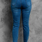 Back view of stylish distressed cropped jeans with frayed hems in blue denim, showcasing casual design and slight stretch fabric.