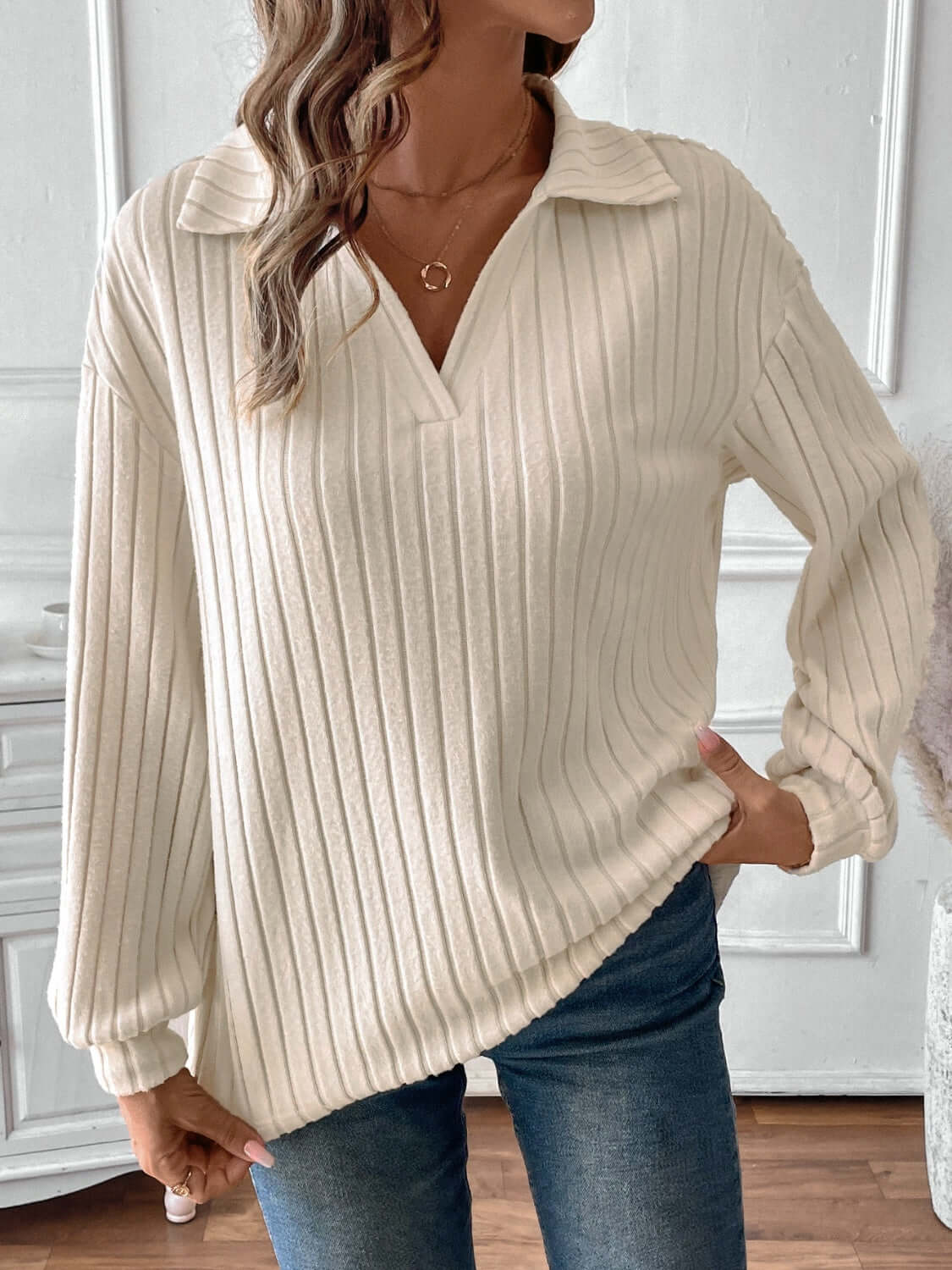 Woman wearing ribbed Johnny collar long sleeve T-shirt in cream, paired with jeans.