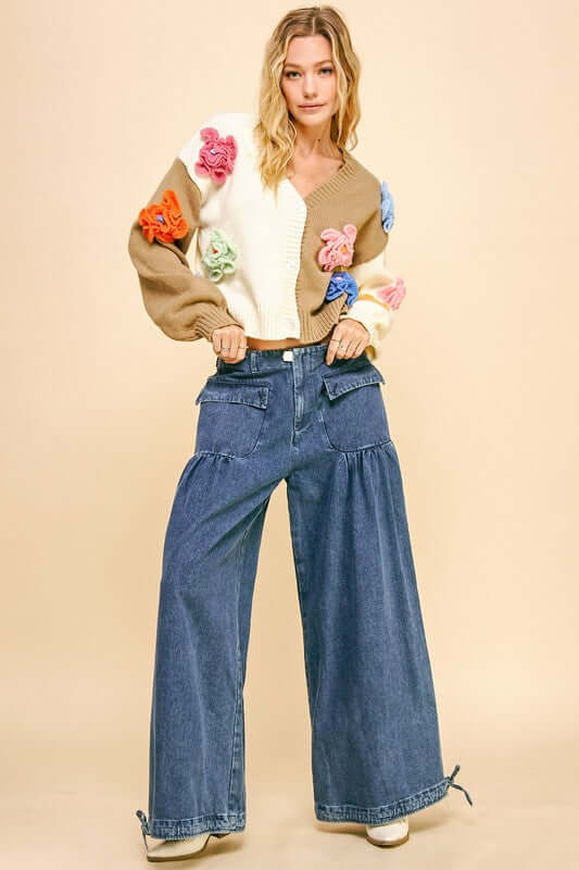 Woman in colorful sweater and wide leg mid-rise jeans, showcasing a trendy, relaxed style with drawstring hem.