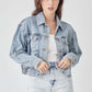 Woman wearing RISEN full size button down cropped denim jacket with distressed shorts, showcasing trendy and fashionable outerwear piece.