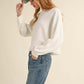 Woman wearing Bella Road Mable Round Neck Dolman Sleeve Cropped Sweater with jeans and a baseball cap.