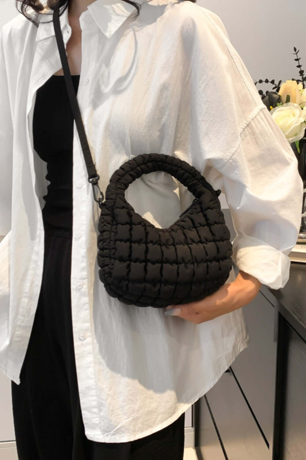 Woman wearing a white shirt and holding a Bella Road Quilted Puffy Crossbody Bag with a removable strap, showcasing its small size and style.