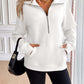 Woman wearing Ivy Lane Half Zip Raglan Sleeve Sweatshirt in white with pocketed design, black shorts, and a small black handbag.