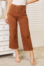 Woman wearing Judy Blue tummy control garment dyed wide crop jeans in brown, full size, paired with a white top and clear heels