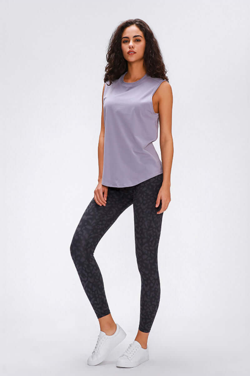 Stylish model wearing Millennia wide seamless band waist sports leggings with a lilac top and white sneakers.