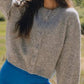 Happy woman in a cozy gray button-down cardigan and blue leggings, enjoying a sunny day outdoors.