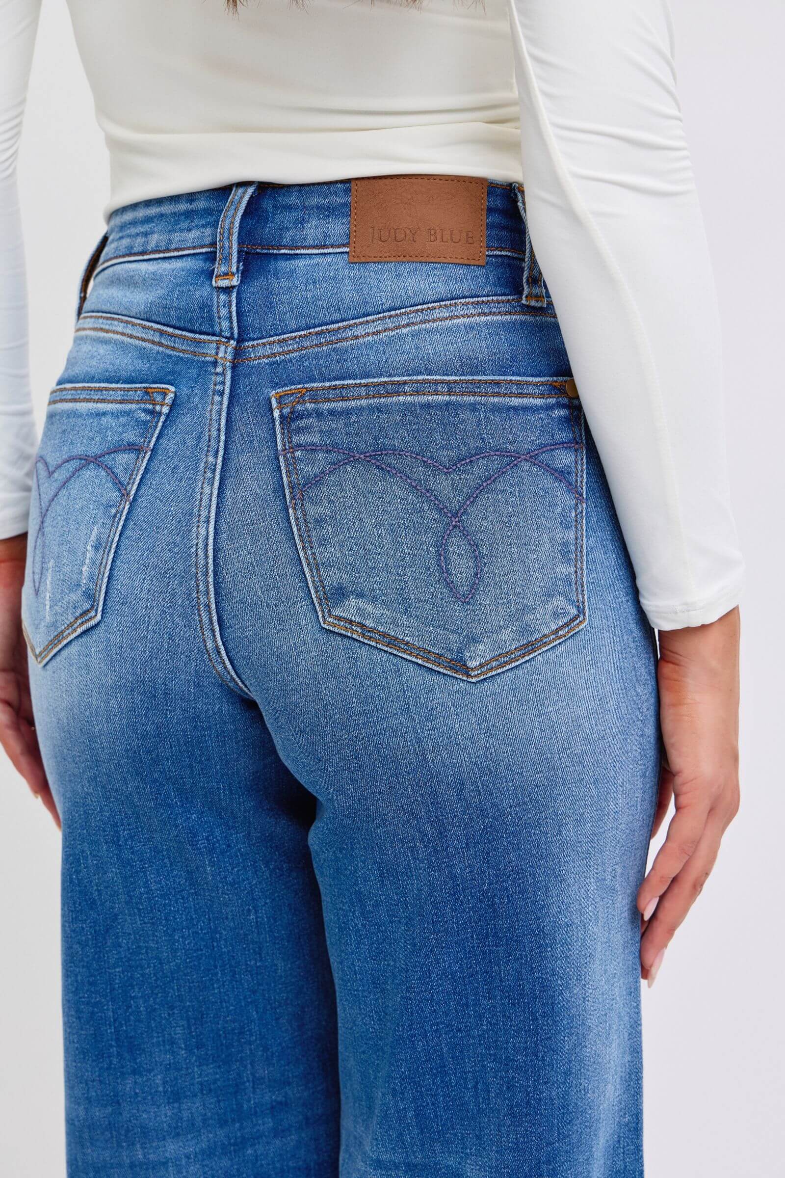 Back view of Judy Blue distressed high waist wide leg jeans, showcasing stylish denim design and pocket detailing.