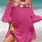 Woman wearing crochet cold shoulder three-quarter sleeve cover-up with ruffled sheer detail in pink on a beach.