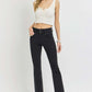 Woman wearing RISEN high-rise wide waistband ankle bootcut jeans in black with a white top, ideal for modern styling.