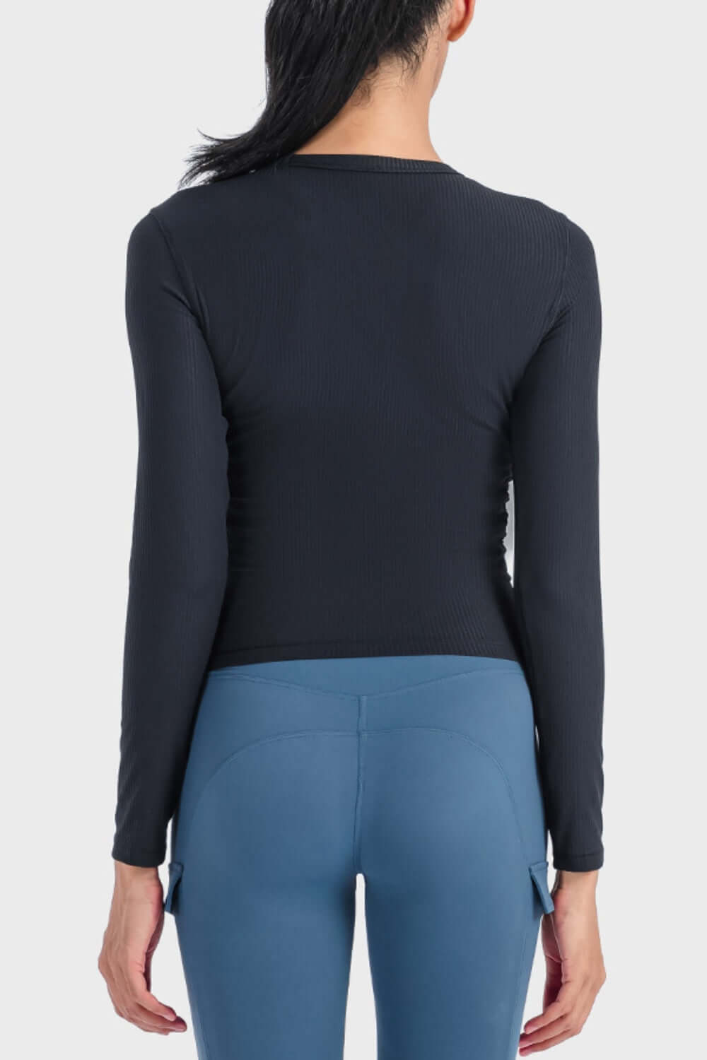 Back view of the Millennia Round Neck Long Sleeve Sports Top paired with stylish blue leggings for a sporty look.