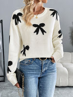 Woman wearing Perfee Bow Graphic Round Neck Long Sleeve Sweater, featuring playful black bow designs, pairing with blue jeans.