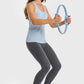 Woman in light blue tank and dark leggings using a fitness ring, showcasing activewear style and workout focus.