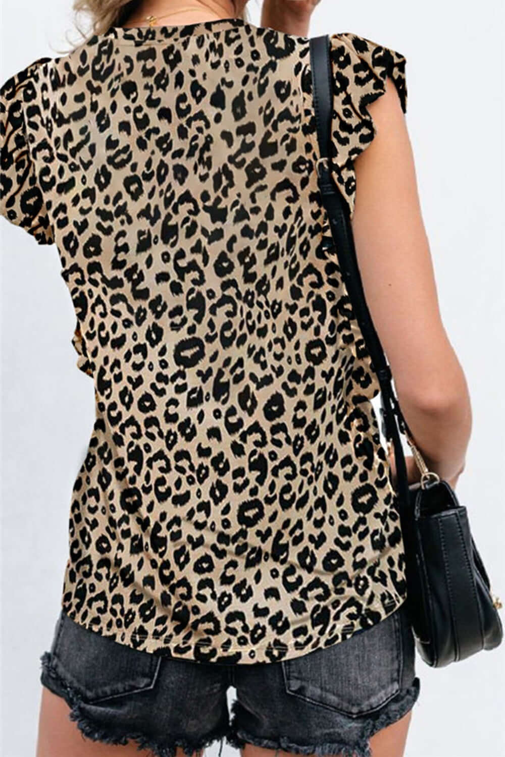 Bella Road leopard print ruffled T-shirt with cap sleeves, round neck, worn with black shorts and a bag, showcasing playful style.