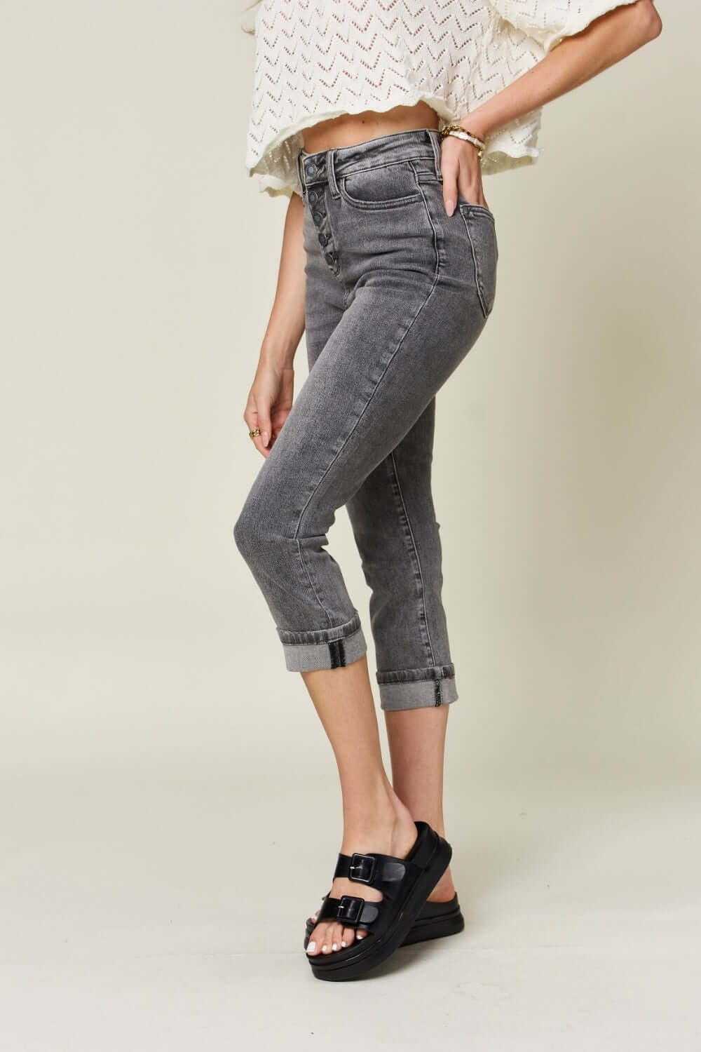 Woman modeling Judy Blue Jeans button fly high waist cuffed capris in gray, highlighting trendy and comfortable design.