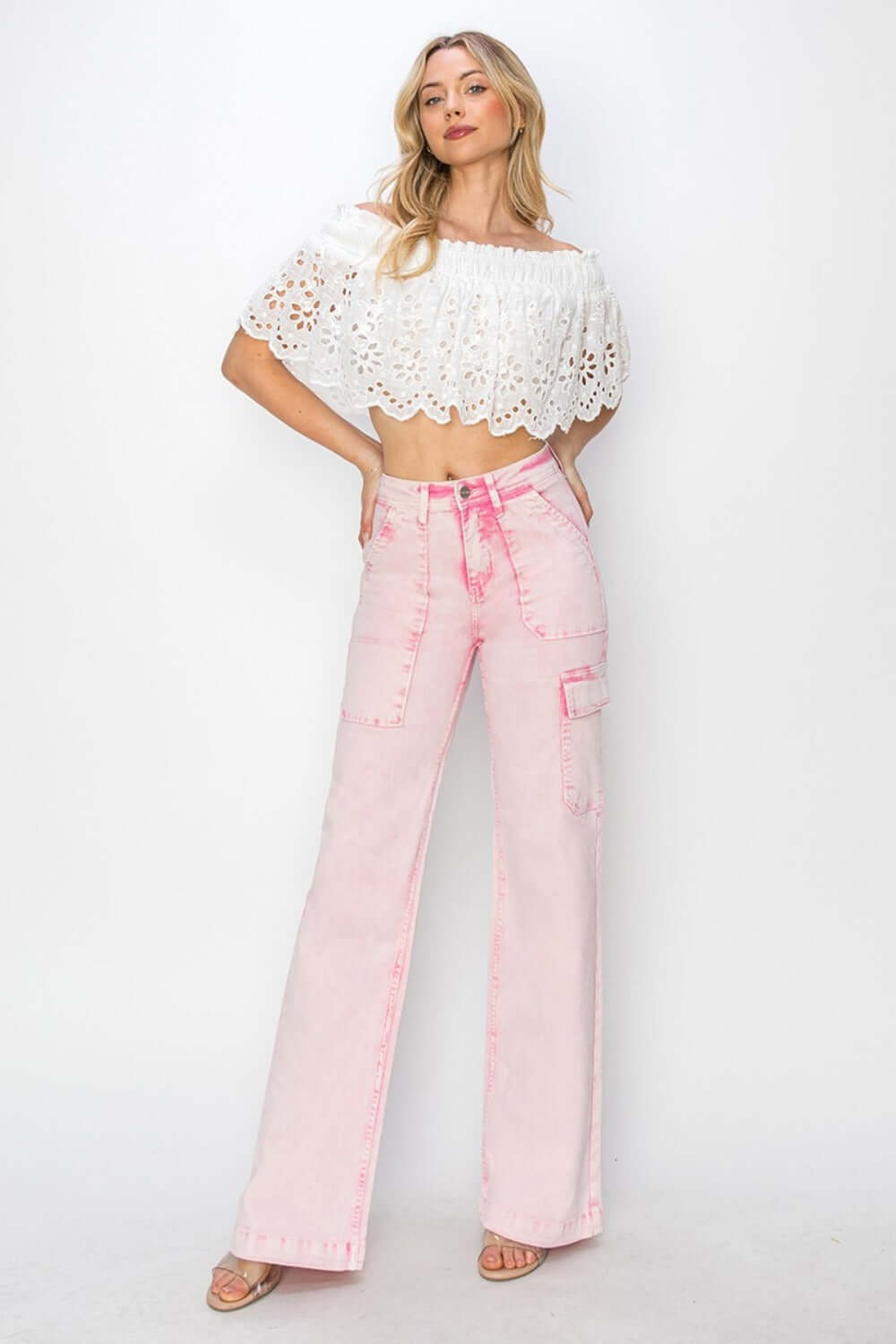 Woman wearing pink high rise wide leg cargo pocket jeans and white lace top, showcasing trendy and functional fashion style.