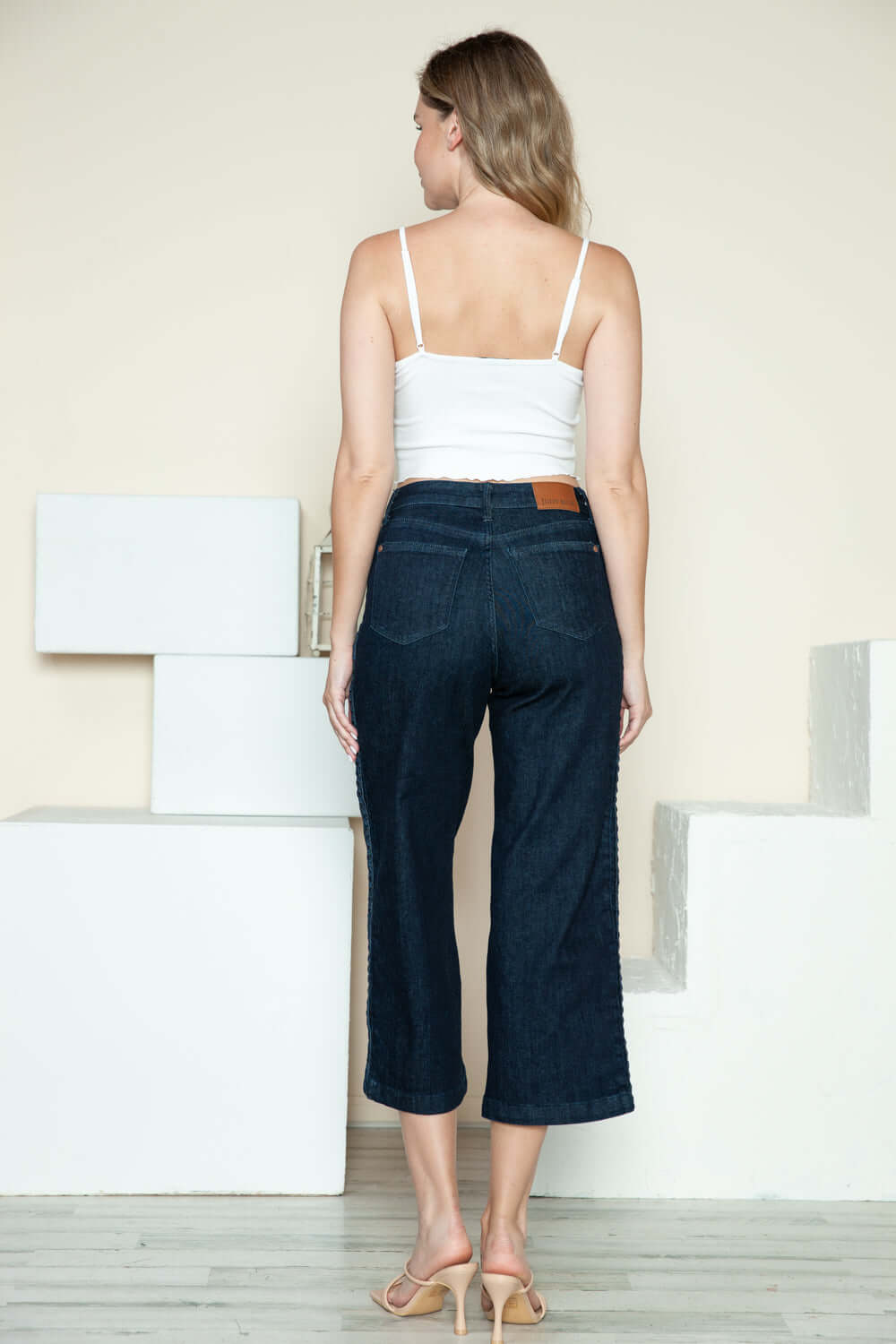 Woman wearing Judy Blue side seam braid detail crop wide leg jeans, showcasing the back view and stylish braided design.