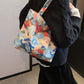 Person carrying a medium-sized printed canvas handbag with a zipper, featuring colorful abstract design. Practical and lightweight at 3.5 oz.