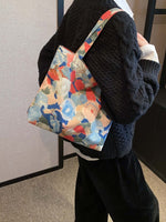 Person carrying a medium-sized printed canvas handbag with a zipper, featuring colorful abstract design. Practical and lightweight at 3.5 oz.