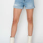 Trendy Risen Jeans Distressed Mid-Rise Denim Shorts styled with white boots for a chic summer look