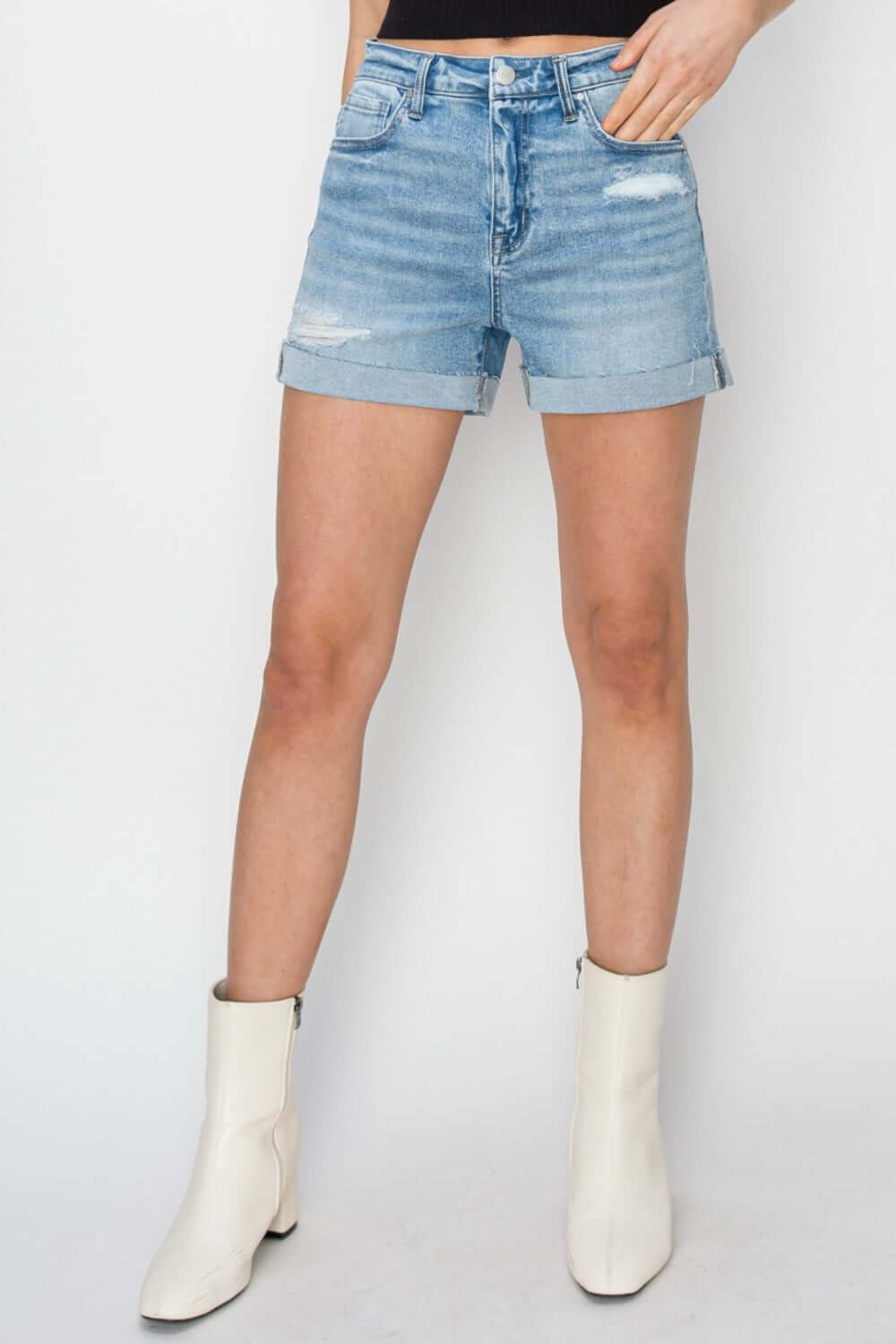 Trendy Risen Jeans Distressed Mid-Rise Denim Shorts styled with white boots for a chic summer look