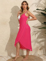 Woman wearing a vibrant pink backless tassel surplice spaghetti strap cover up dress made of 100% polyester.