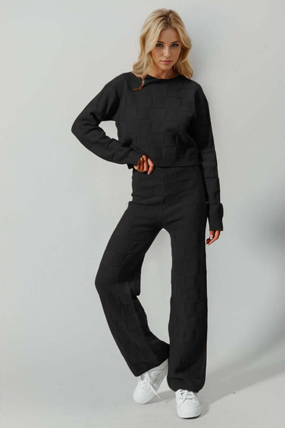 Stylish woman in a full-size checkered round neck top and pants set, showcasing edgy leisurewear in classic black with moderate stretch.