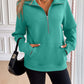 Woman wearing Ivy Lane Half Zip Raglan Sleeve Sweatshirt in green with front pockets and black shoulder bag