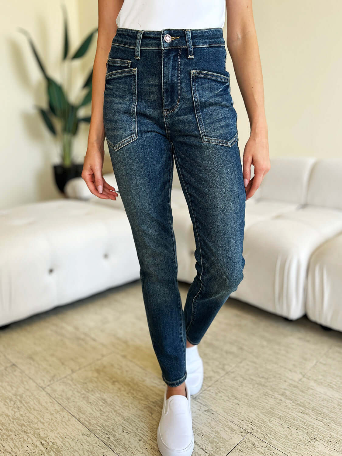 Woman wearing high waist skinny Judy Blue Jeans in dark denim with a modern skinny leg silhouette and front pockets, standing indoors.