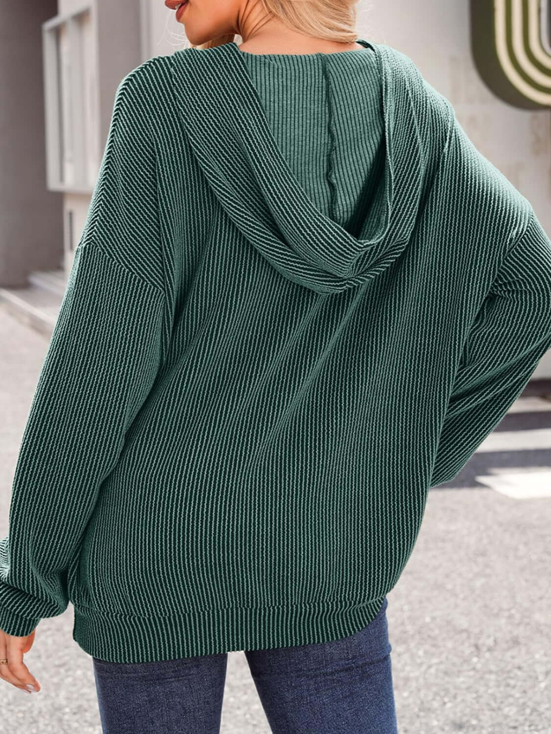 Woman wearing a green textured kangaroo pocket long sleeve hoodie seen from the back