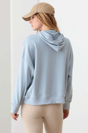 Woman wearing Tasha Apparel Half Zip Drawstring Mock Neck Hoodie in light blue, back view.