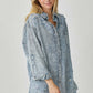 Woman wearing a distressed raw hem denim shirt from Risen Jeans, showing off its casual and edgy style with frayed edges.