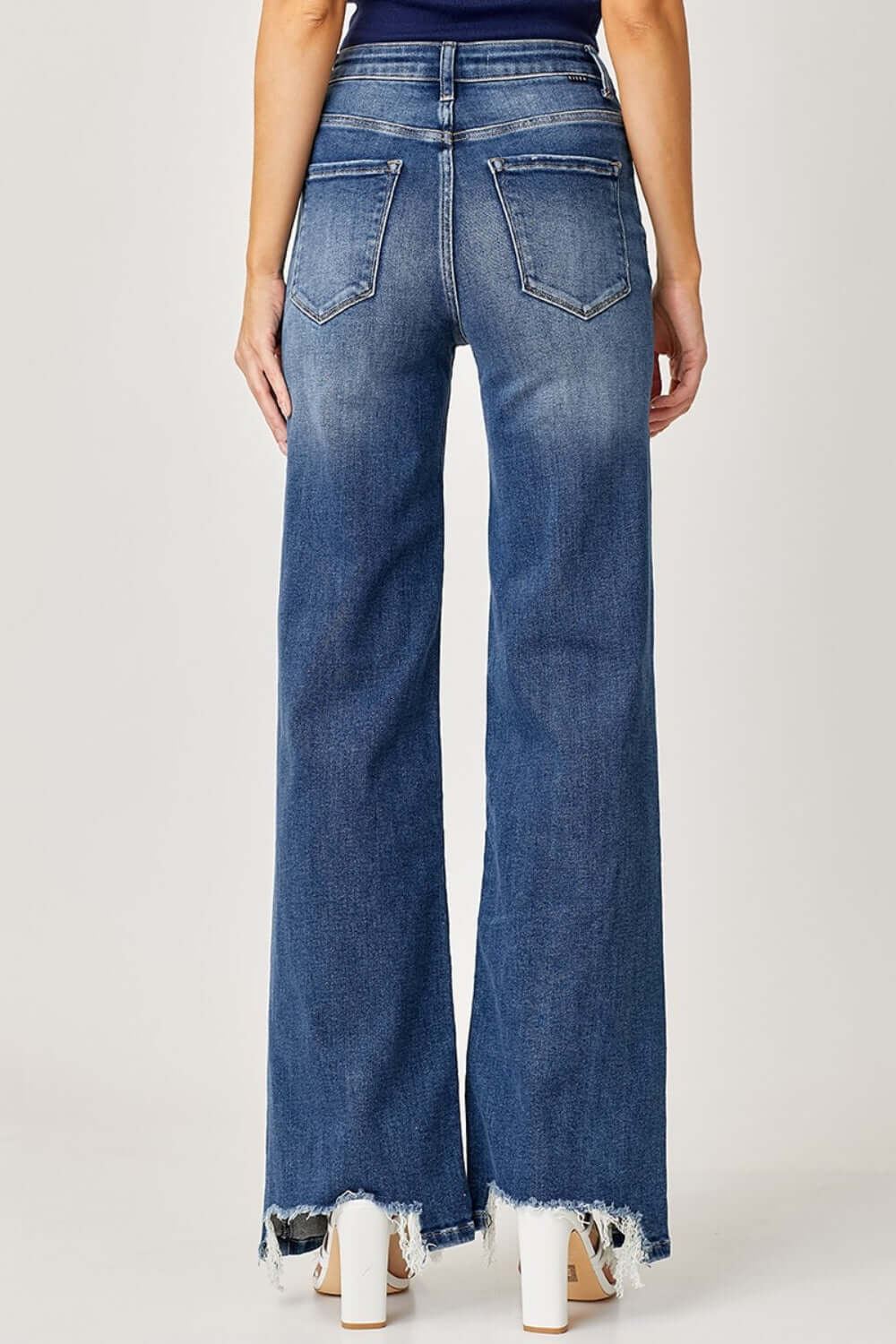 Woman wearing High Rise Frayed Hem Wide Leg Jeans from Risen Jeans, showcasing retro style with a flattering fit and trendy frayed hem.