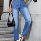 Stylish woman wearing Bella Road Denim Straight Leg Jeans, black crop top, and sneakers, posing on stairs with a handbag.