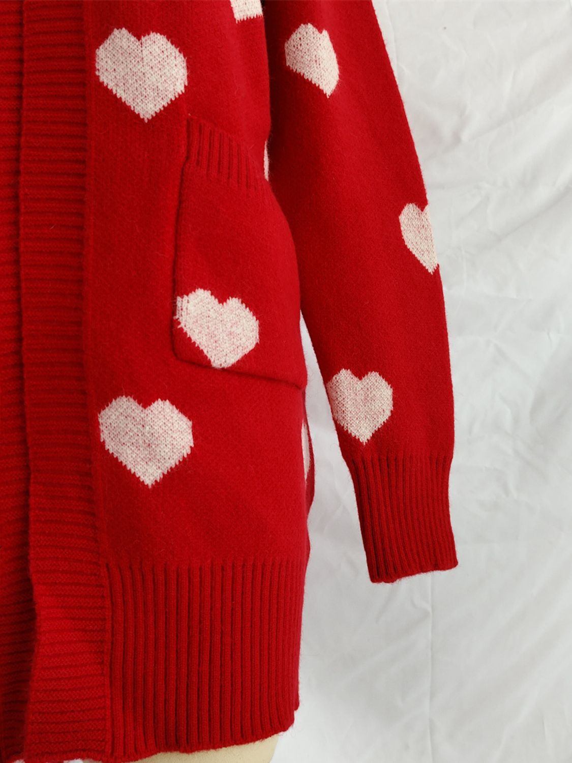 Close-up of Bella Road Heart Open Front Long Sleeve Cardigan in red with white heart patterns and pocket detail.