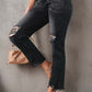 Woman wearing stylish distressed cropped jeans in black with a solid pattern, featuring rips and slightly stretchy material.