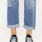 Mid rise distressed straight jeans with cuffed hems and black sneakers for a trendy, casual look.