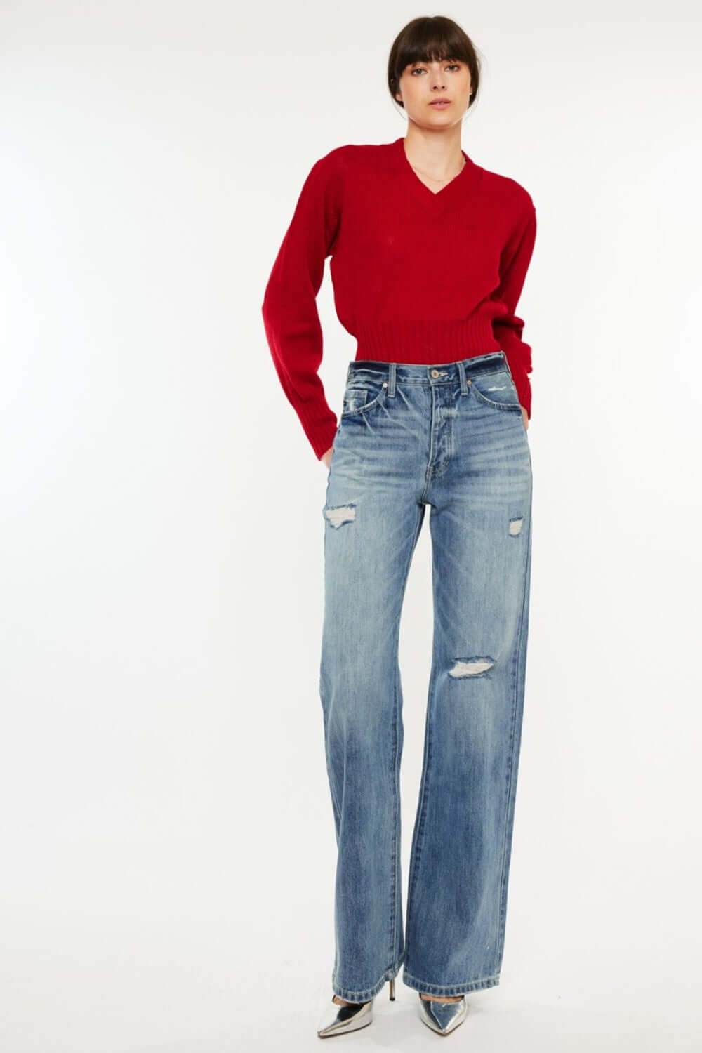 Woman wearing distressed high waist bootcut jeans with a red sweater, showcasing retro-chic style perfect for casual or elegant outfits.