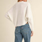 Woman wearing Bella Road Mable Round Neck Dolman Sleeve Cropped Sweater paired with jeans and a baseball cap, showing back view.